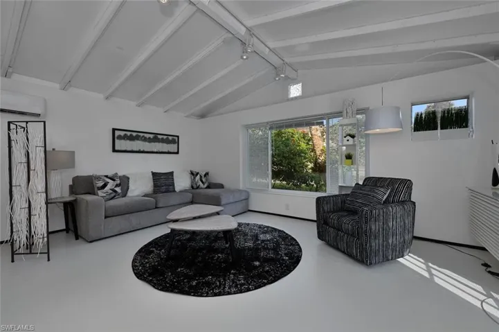 Living area with a wall unit AC, healthy amount of natural light, and finished concrete floors