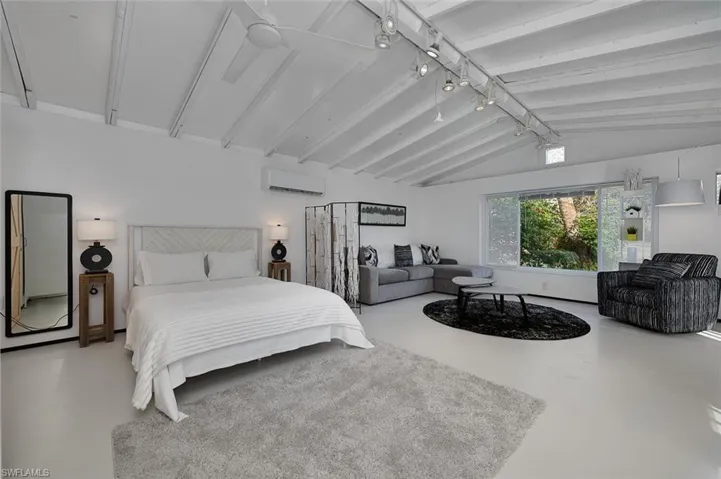 Bedroom with a wall mounted air conditioner and concrete flooring