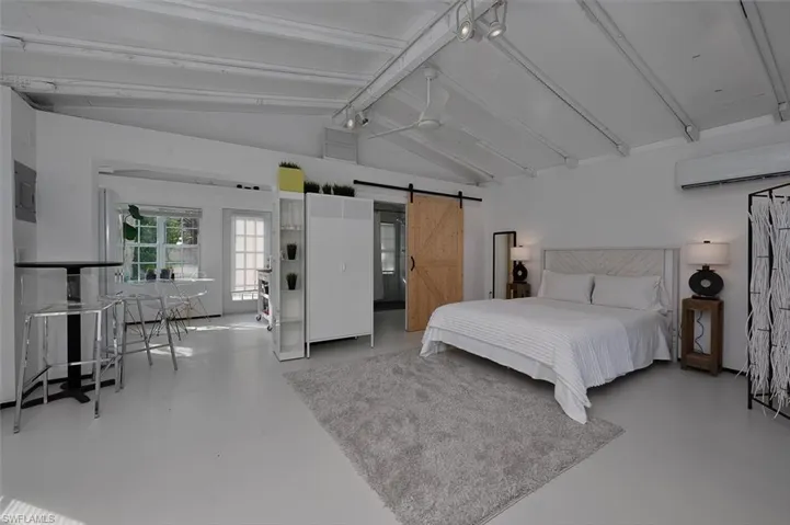 Bedroom featuring concrete flooring, a barn door, and a wall unit AC