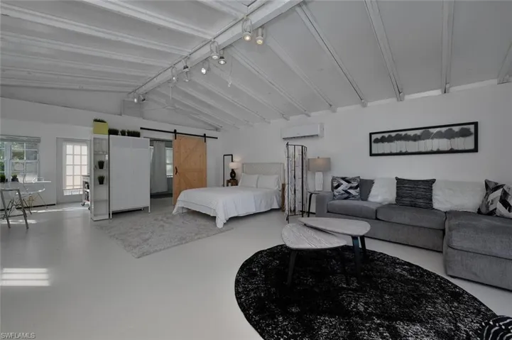Bedroom featuring a wall mounted air conditioner, a barn door, and finished concrete floors