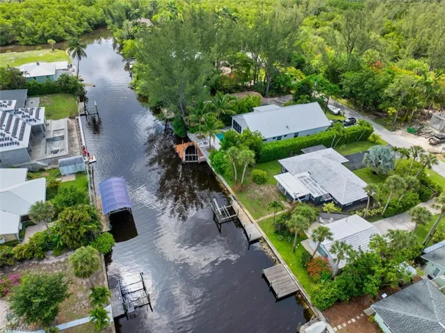 Aerial perspective of suburban area featuring a nearby body of water and a forest
