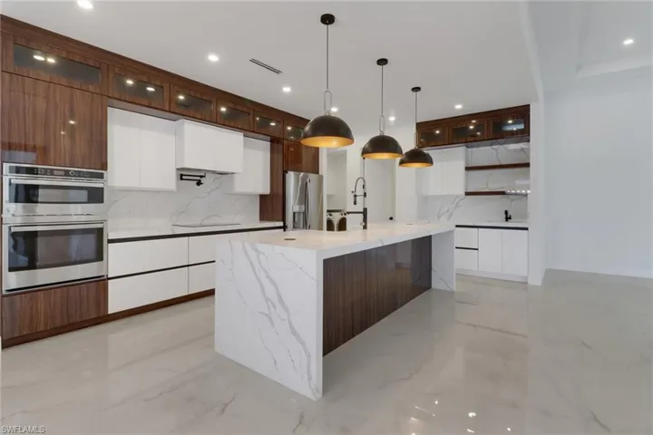 Kitchen featuring marble finish floor, modern cabinets with stainless steel appliances