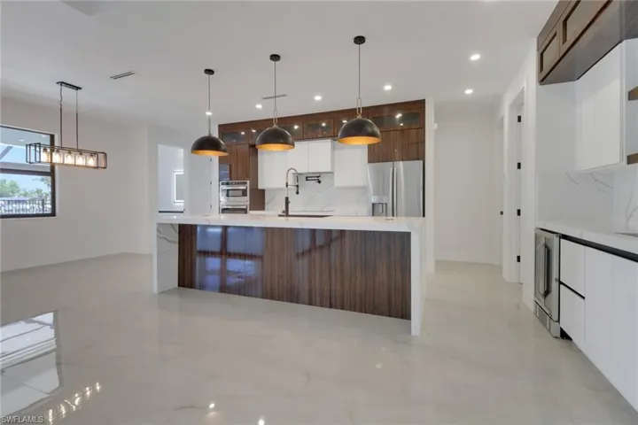 Kitchen with modern cabinets and island featuring waterfall quartz
