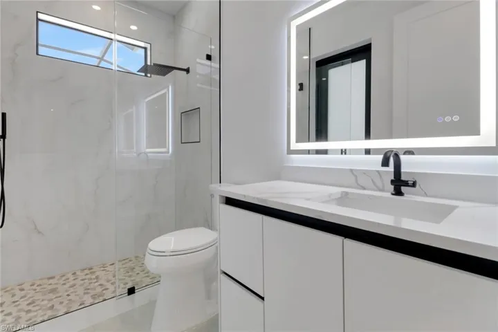 Pool Access Bathroom with a marble finish shower, toilet, and vanity (Bathroom 2 )