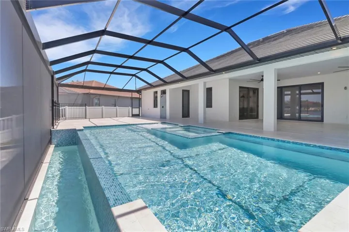 View of infinity edge swimming pool featuring a hot tub, and sun shelf