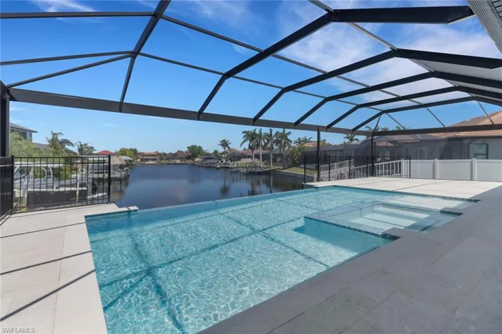 View of pool with a water view, screen enclosure, a heated spa, and a patio