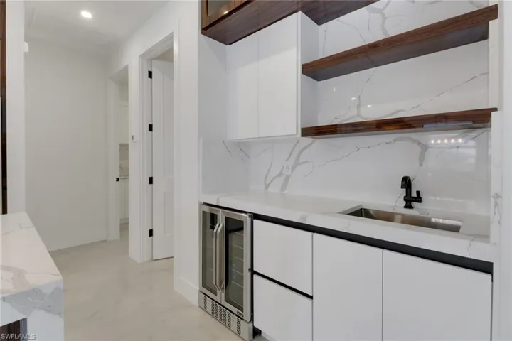 Kitchen with custom shelving, a beverage sink and wine cooler