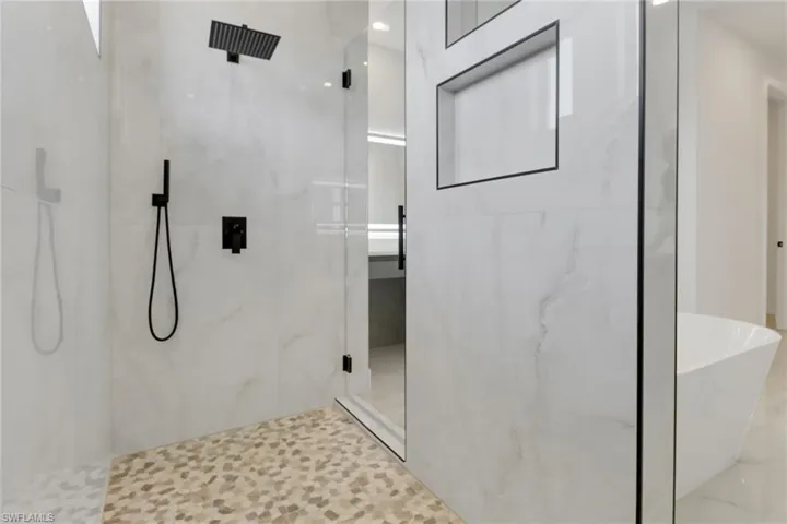 Bathroom featuring a soaking tub and a marble finish shower