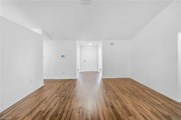 Open living area featuring wood-finish flooring, white baseboards, and textured white walls