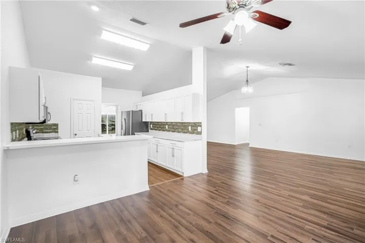 Vaulted ceilings over wood-finish flooring throughout the open concept kitchen and living area