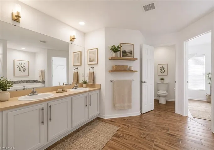 Double vanity with light countertops and white cabinetry, featuring individual sinks and brass-toned wall sconces