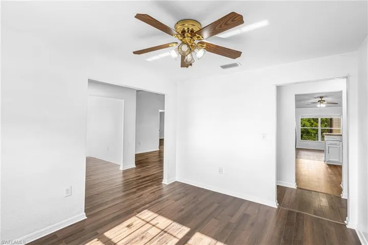 Interior space featuring wood-finish flooring, white painted walls, and a ceiling fan with integrated lighting