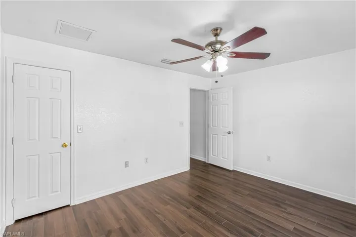 Interior space featuring wood-finish flooring, white walls, and a ceiling fan with integrated lighting