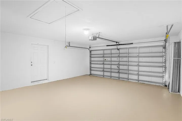 Spacious garage featuring a light-toned finished floor, white walls, and a white paneled entry door