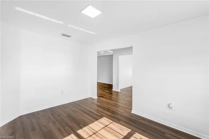 Interior room featuring wood-finish flooring, white baseboards, and a square recessed ceiling light