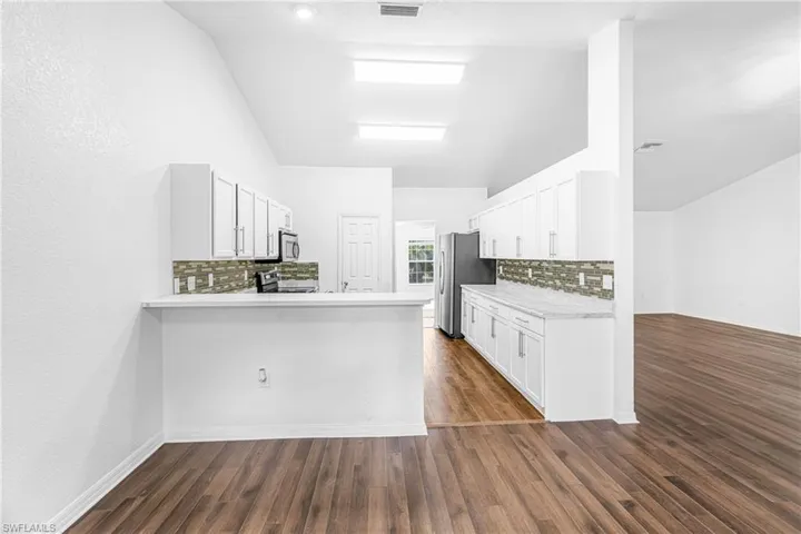 Kitchen featuring white cabinetry, light-toned countertops, and a mosaic tile backsplash