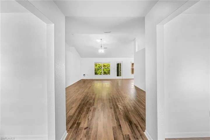 Expansive interior space featuring wood-finish flooring, vaulted ceilings, and a neutral color palette