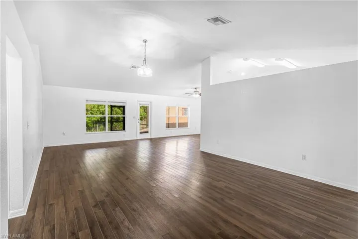 Spacious interior featuring wood-finish flooring, vaulted ceilings, and white walls