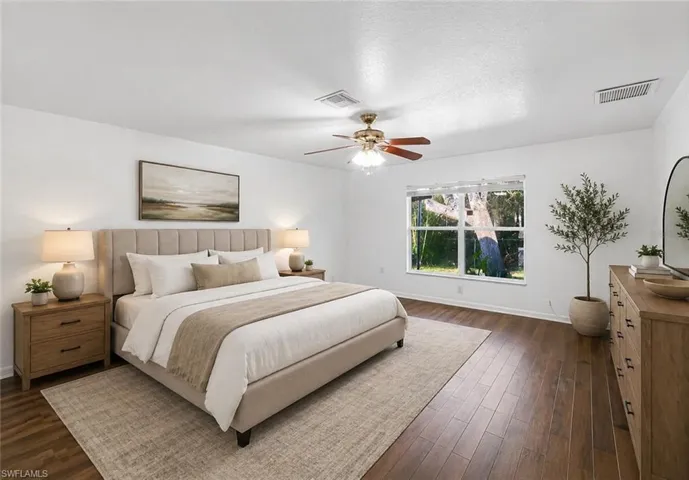 Spacious room featuring wood-finish flooring, white walls, and a large window