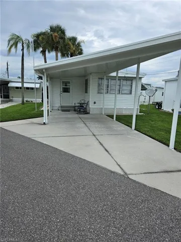 View of front of property with a carport and a front yard