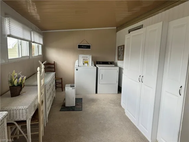 Clothes washing area with light colored carpet, washer and dryer, crown molding, and wooden ceiling