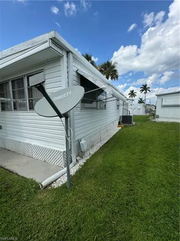 View of home's exterior with central AC unit and a yard