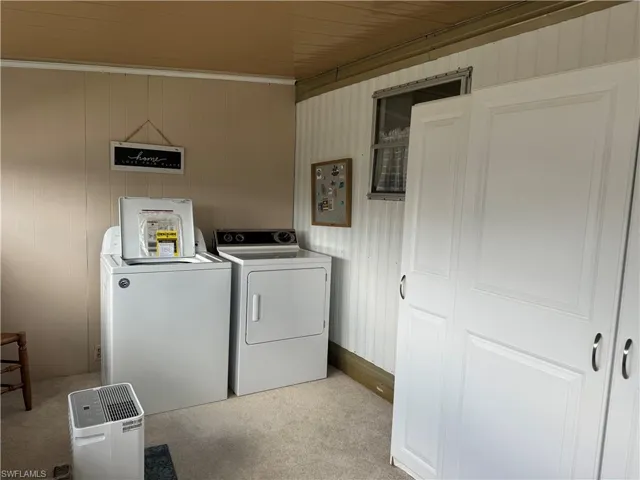 Laundry room with independent washer and dryer and light colored carpet