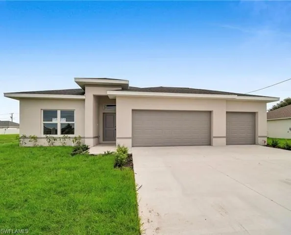 Prairie-style home featuring an attached garage, driveway, a front lawn, and stucco siding