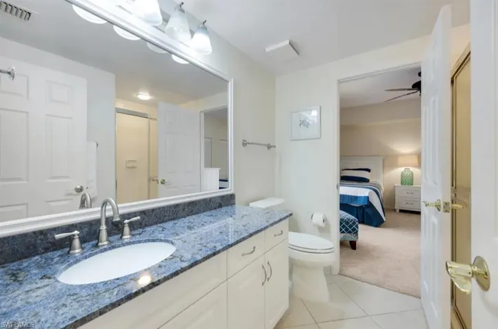 Ensuite bathroom with vanity, tile patterned flooring, toilet, and an enclosed shower