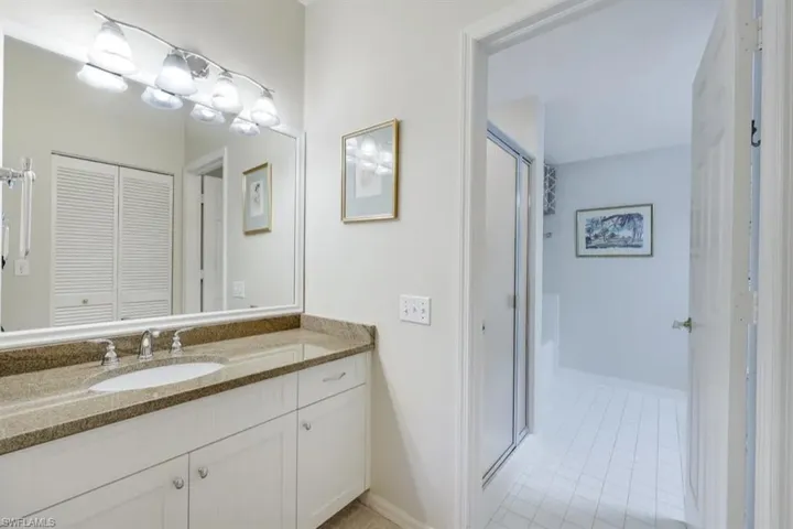Bathroom featuring vanity, tile patterned floors, baseboards, a shower with shower door, and a closet