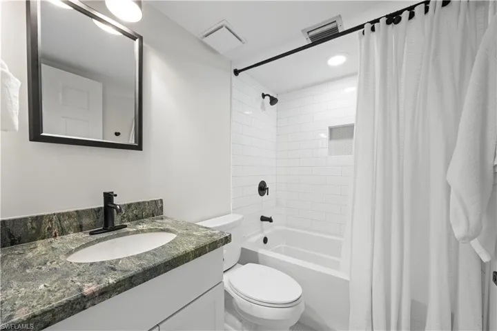Full bathroom featuring toilet, vanity, and shower / bathtub combination with curtain