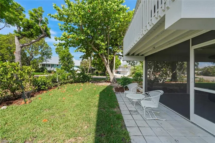 View of grassy yard with a screened porch and a patio