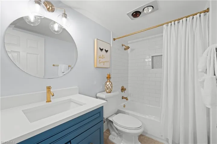 Bathroom with toilet, shower / bathtub combination with curtain, and vanity