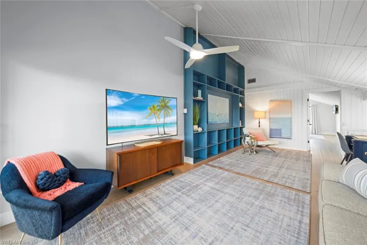 Living room featuring wood finished floors, lofted ceiling, a ceiling fan, and wooden ceiling