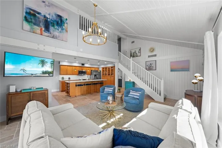 Living room featuring a chandelier, baseboards, stairway, and high vaulted ceiling
