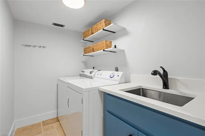 Washroom with washer and clothes dryer, baseboards, light stone finish flooring, and cabinet space