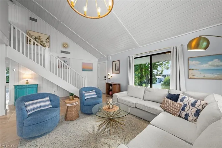 Living area with stairs, high vaulted ceiling, and a chandelier