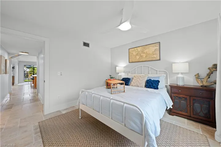 Bedroom featuring stone tile floors, baseboards, and a ceiling fan