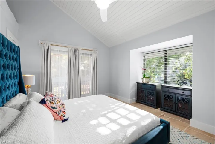 Bedroom featuring light tile patterned floors, lofted ceiling, baseboards, and a ceiling fan