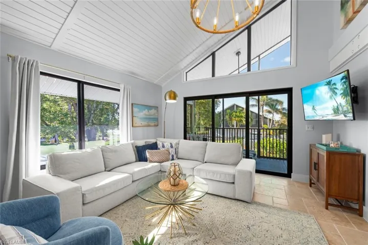 Living area with stone tile flooring, a chandelier, and high vaulted ceiling