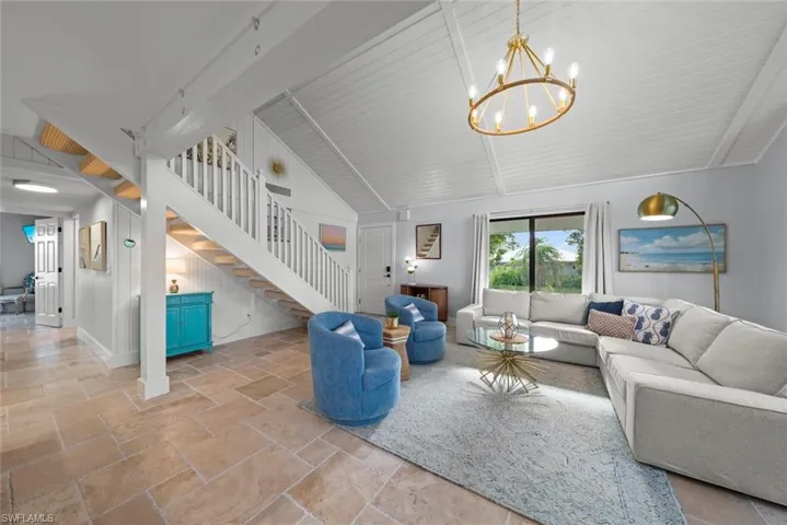 Living area with stone tile flooring, stairs, and a chandelier