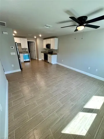 Unfurnished living room featuring ceiling fan and wood tiled floors