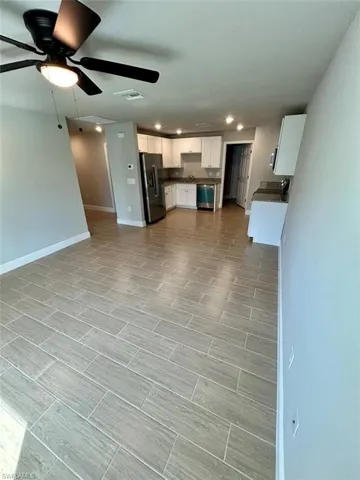Kitchen with white cabinets, stainless steel appliances, recessed lighting, ceiling fan, and wood tiled floors