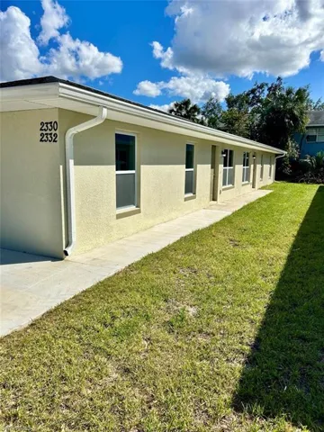 View of side of home with stucco siding and a yard