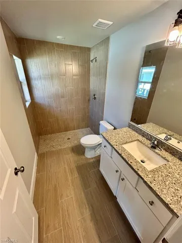 Full bath with a tile shower, vanity, and wood tiled floors