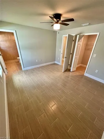 Unfurnished bedroom featuring a spacious closet, wood tiled floors, a ceiling fan, and a textured ceiling