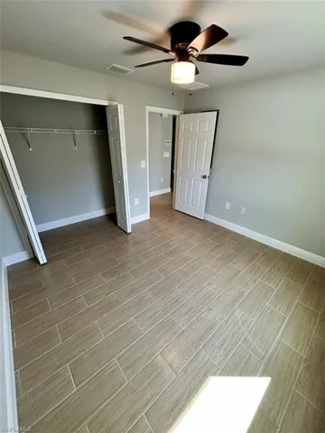 Unfurnished bedroom featuring ceiling fan, a closet, and wood tiled floors