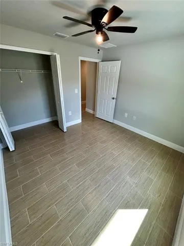 Unfurnished bedroom with ceiling fan, wood tiled floors, and a closet