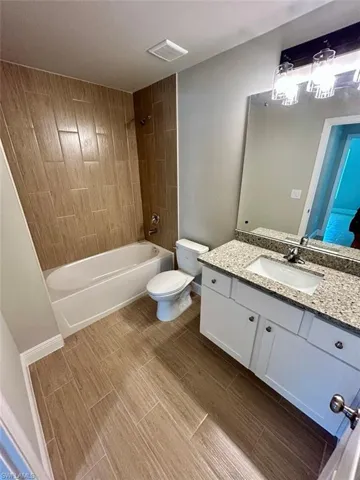 Full bathroom with vanity, washtub / shower combination, and wood tiled floors