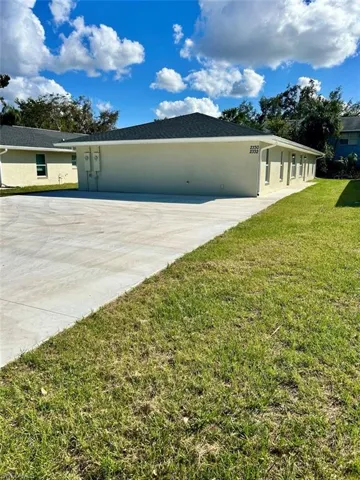 View of home's exterior with a lawn, concrete driveway, and stucco siding